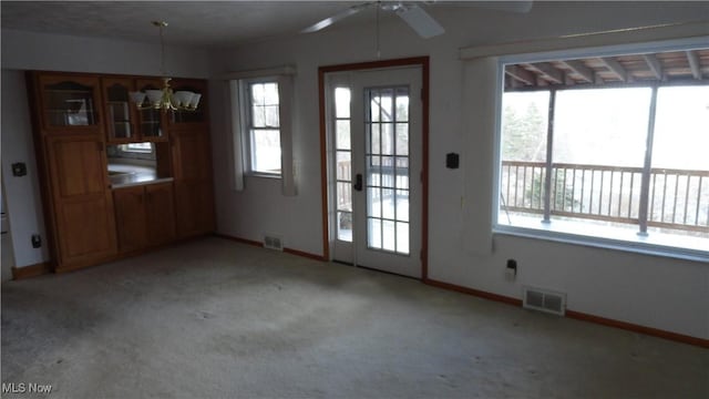 interior space featuring light carpet and ceiling fan with notable chandelier