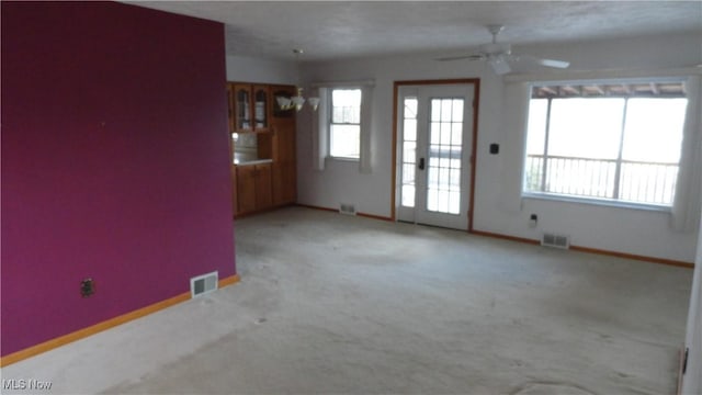 empty room with ceiling fan, light colored carpet, a textured ceiling, and french doors