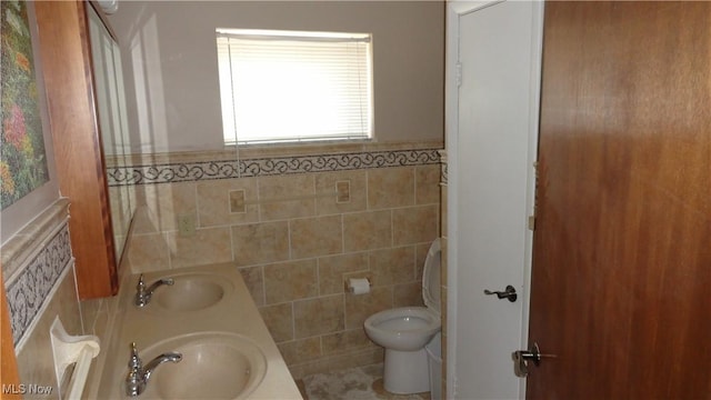 bathroom featuring vanity, tile walls, and toilet