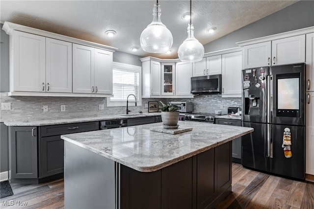 kitchen with a textured ceiling, appliances with stainless steel finishes, vaulted ceiling, and white cabinets