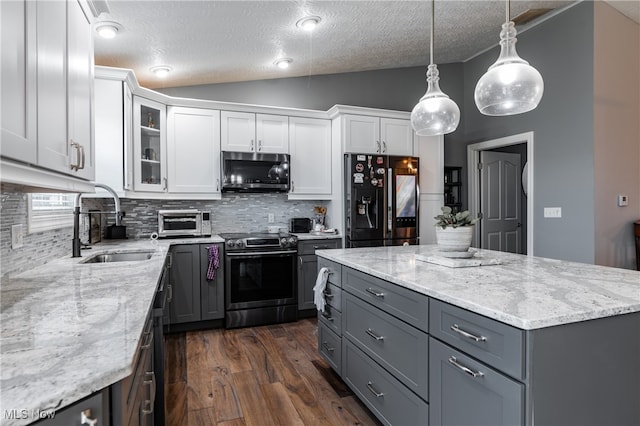 kitchen featuring lofted ceiling, a textured ceiling, white cabinetry, appliances with stainless steel finishes, and decorative light fixtures