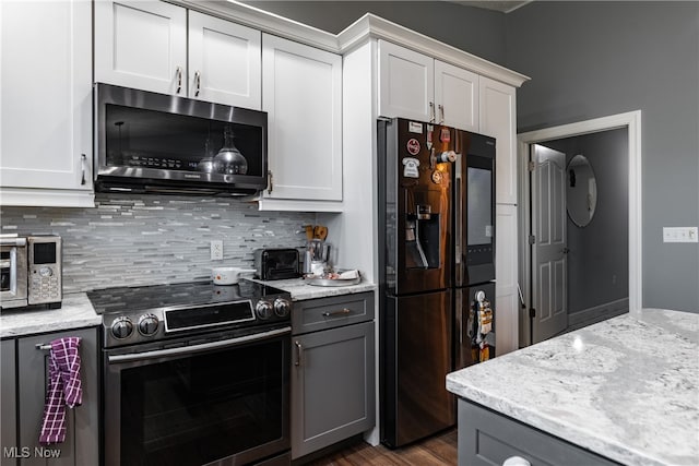 kitchen with white cabinetry, light stone counters, dark hardwood / wood-style floors, and stainless steel appliances