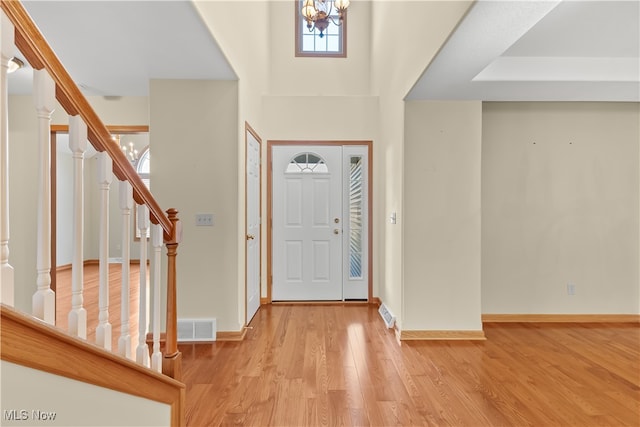 entryway with a notable chandelier, a high ceiling, and light hardwood / wood-style flooring