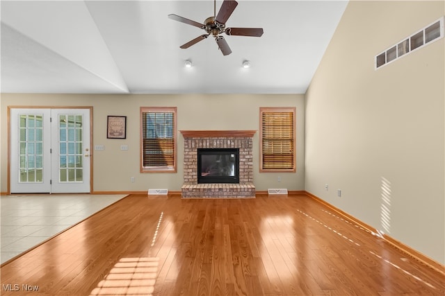 unfurnished living room with ceiling fan, light hardwood / wood-style floors, a fireplace, and vaulted ceiling