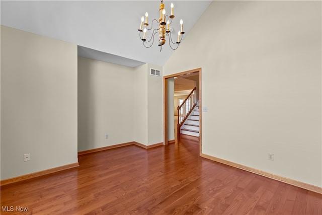 spare room with high vaulted ceiling, a chandelier, and wood-type flooring