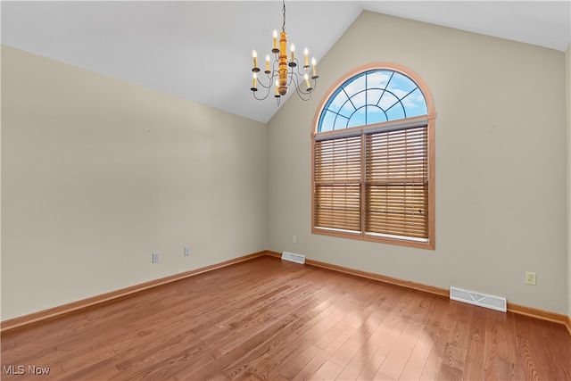 unfurnished room with a notable chandelier, lofted ceiling, and hardwood / wood-style flooring