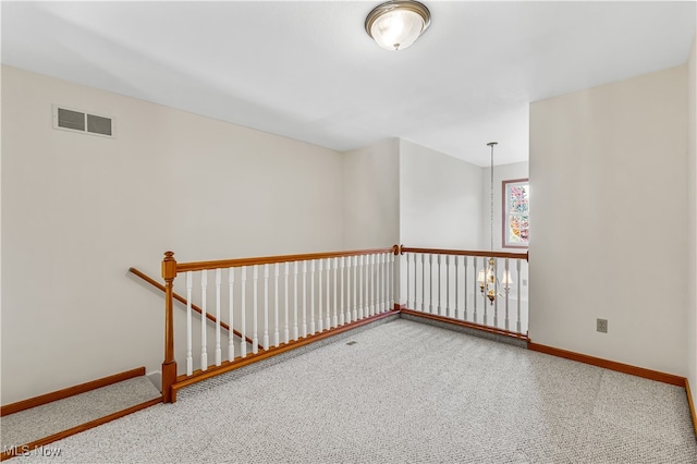 carpeted spare room featuring a chandelier