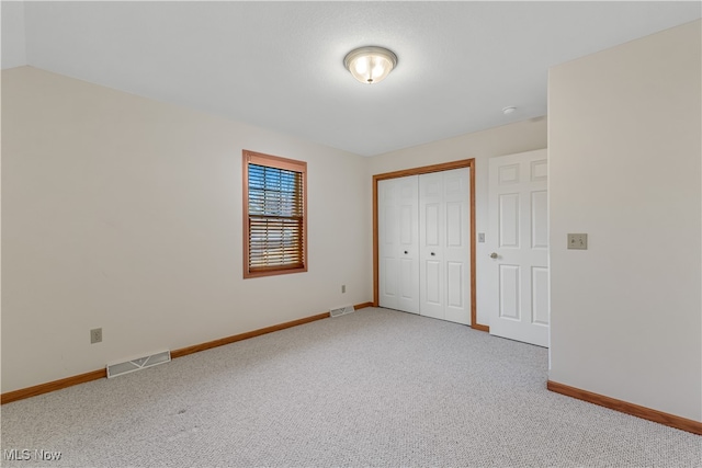 unfurnished bedroom featuring carpet, lofted ceiling, and a closet