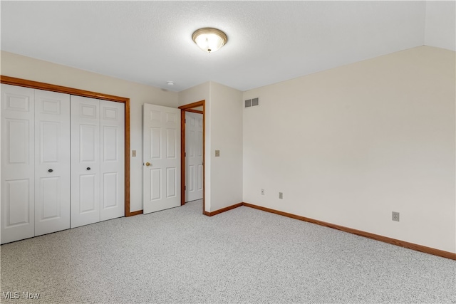 unfurnished bedroom featuring carpet floors, a closet, and lofted ceiling