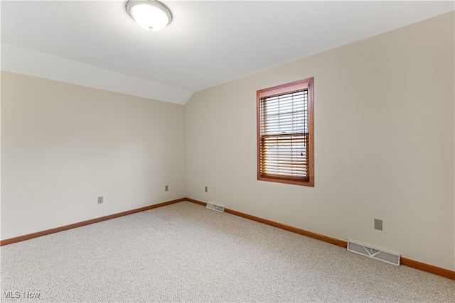 carpeted empty room featuring lofted ceiling