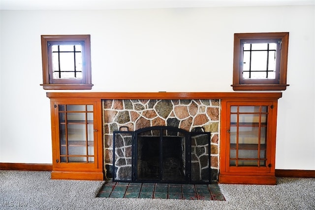 interior details featuring a stone fireplace and carpet floors