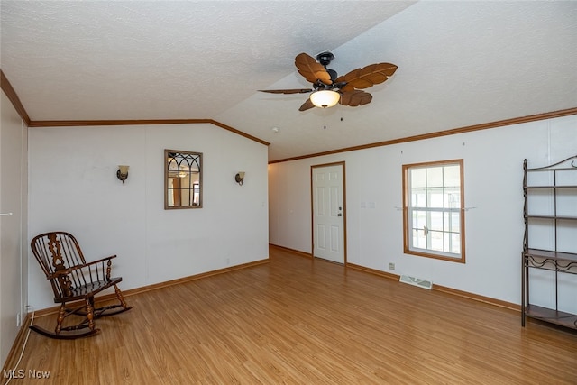 living area featuring light hardwood / wood-style flooring, a textured ceiling, ceiling fan, and vaulted ceiling