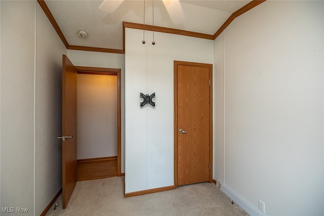 unfurnished bedroom featuring a textured ceiling, light colored carpet, ornamental molding, and ceiling fan