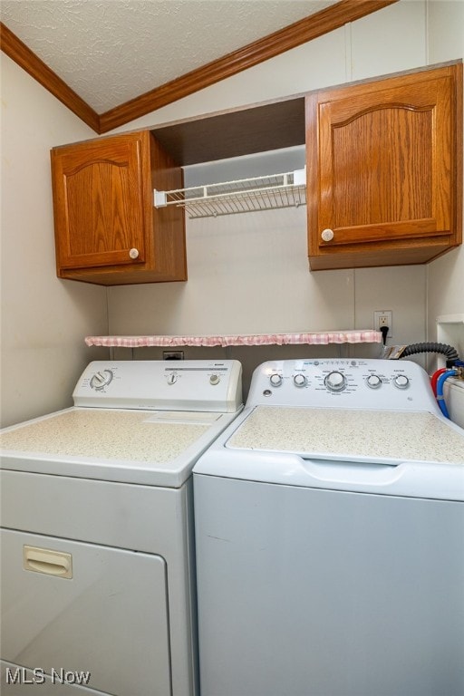 washroom with ornamental molding, separate washer and dryer, a textured ceiling, and cabinets