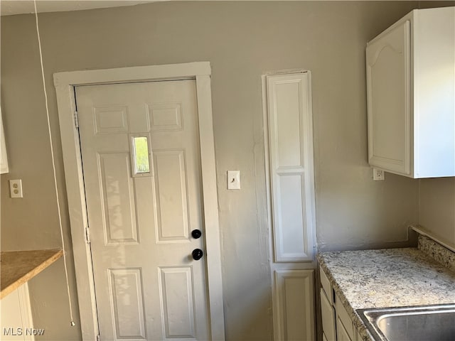 kitchen featuring white cabinetry and light stone counters