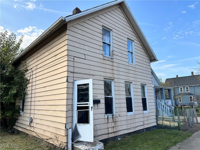 view of side of property with fence and a chimney