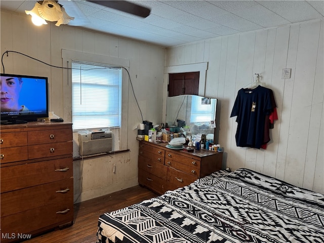 bedroom with multiple windows, wooden walls, and dark hardwood / wood-style floors