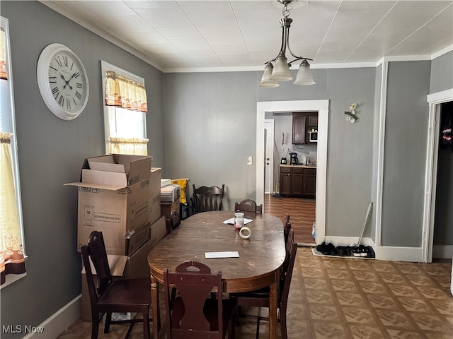 dining space with wood walls, hardwood / wood-style flooring, crown molding, and a notable chandelier