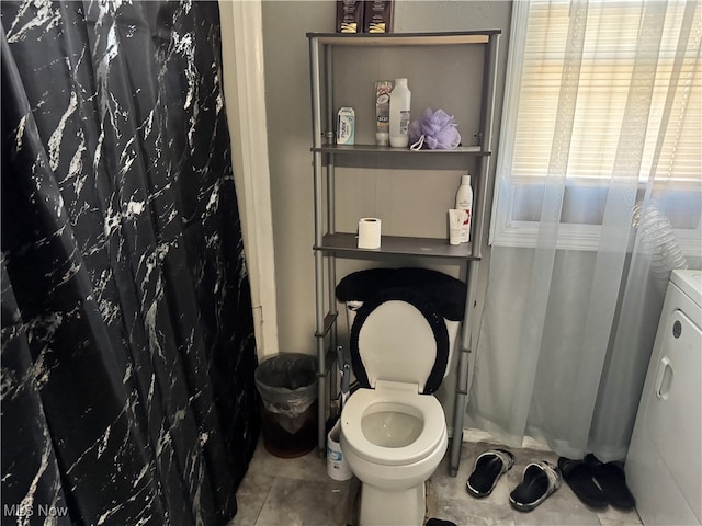 bathroom with a shower with shower curtain, tile patterned floors, toilet, and washer / clothes dryer