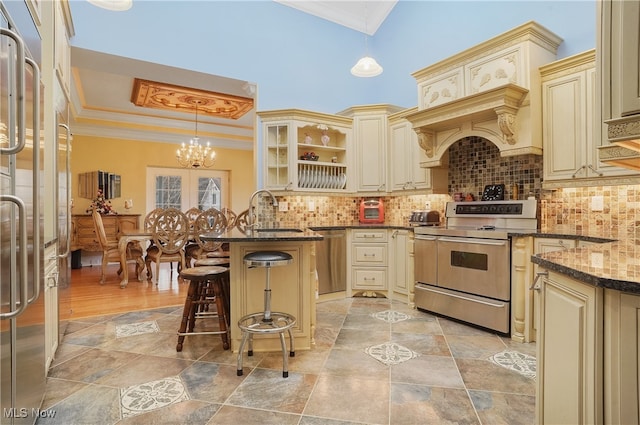 kitchen featuring a breakfast bar, appliances with stainless steel finishes, cream cabinetry, and hanging light fixtures