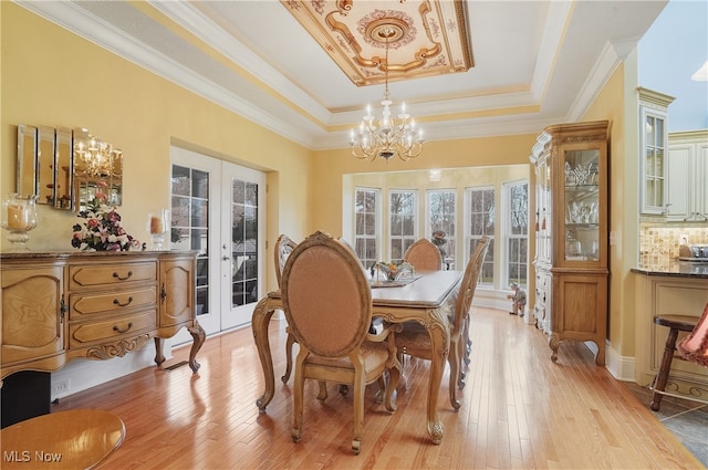 dining space featuring plenty of natural light, a raised ceiling, and light wood-type flooring