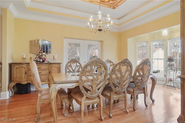 dining room featuring ornamental molding, light hardwood / wood-style floors, a raised ceiling, and an inviting chandelier