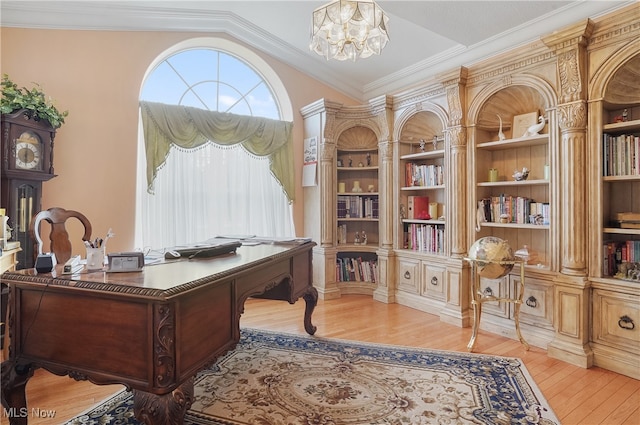 home office featuring lofted ceiling, built in shelves, a chandelier, crown molding, and light wood-type flooring