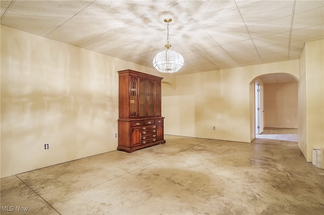 unfurnished living room with a chandelier and concrete floors