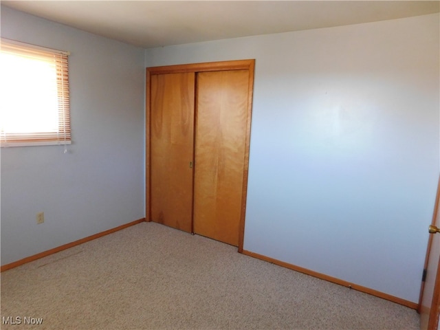 unfurnished bedroom with light carpet and a closet