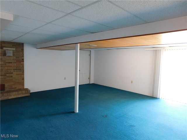 basement with a paneled ceiling and dark carpet