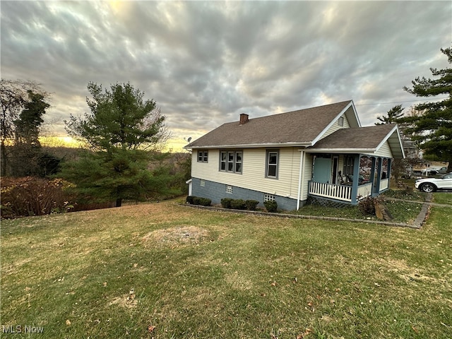 property exterior at dusk featuring a porch and a yard