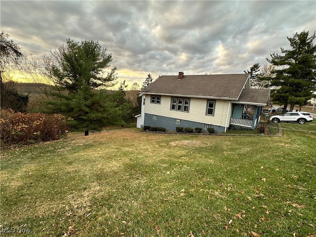 property exterior at dusk featuring a lawn