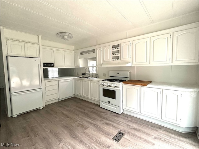 kitchen with white cabinetry, light hardwood / wood-style flooring, sink, and white appliances