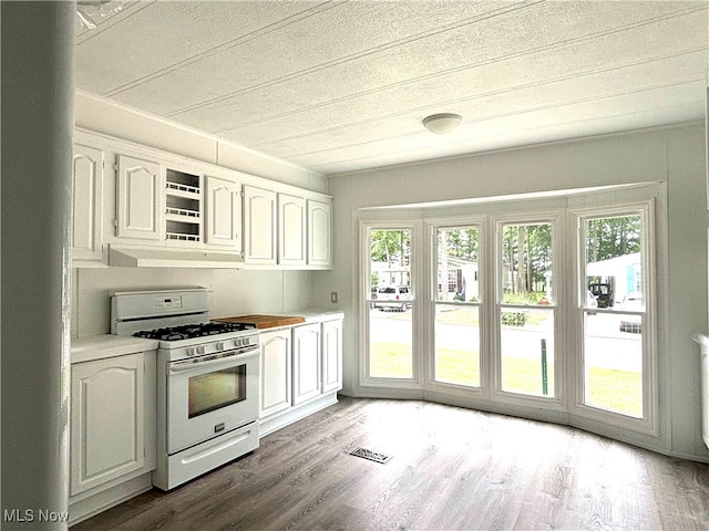 kitchen featuring hardwood / wood-style floors, white gas stove, and white cabinets