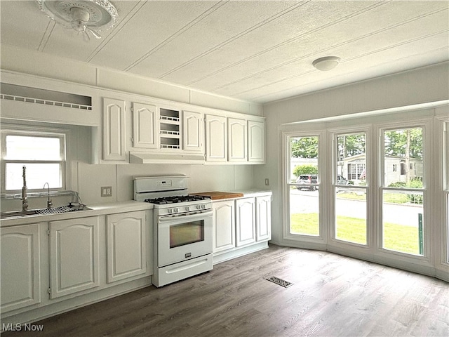 kitchen with white cabinetry, a wealth of natural light, gas range gas stove, and light hardwood / wood-style flooring