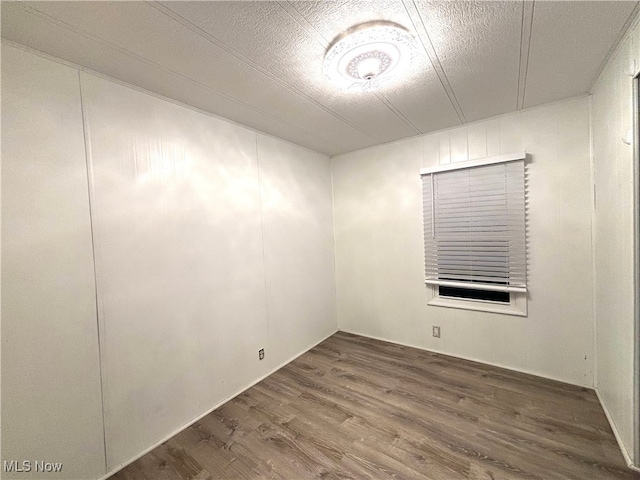 empty room featuring wood-type flooring and a textured ceiling