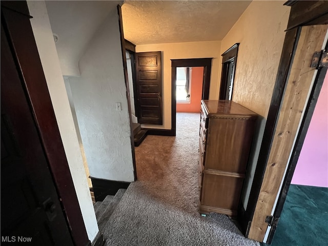 corridor with a textured ceiling and dark carpet