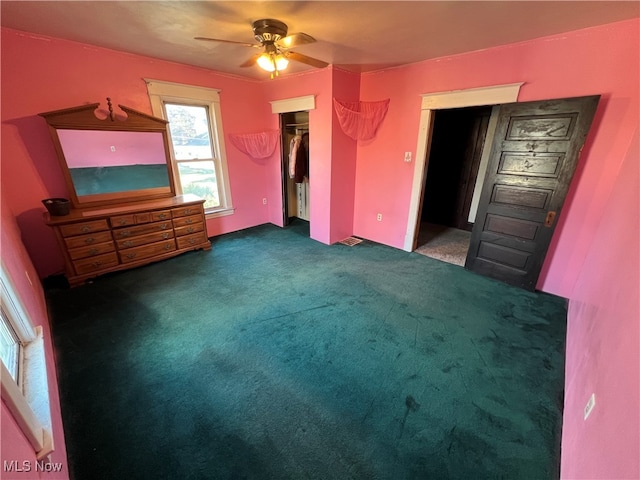 unfurnished bedroom with dark colored carpet, ceiling fan, and a closet