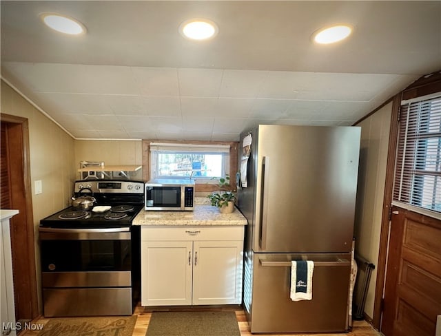 kitchen featuring stainless steel appliances, lofted ceiling, and white cabinets