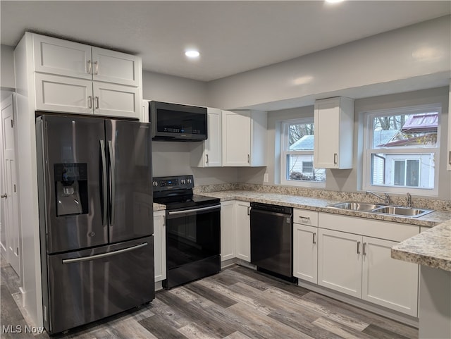 kitchen with white cabinets, wood-type flooring, sink, and black appliances