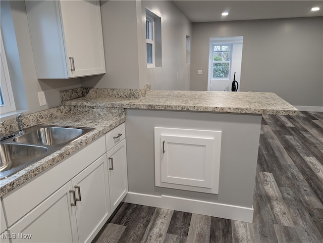 kitchen featuring white cabinets, dark hardwood / wood-style floors, kitchen peninsula, and sink