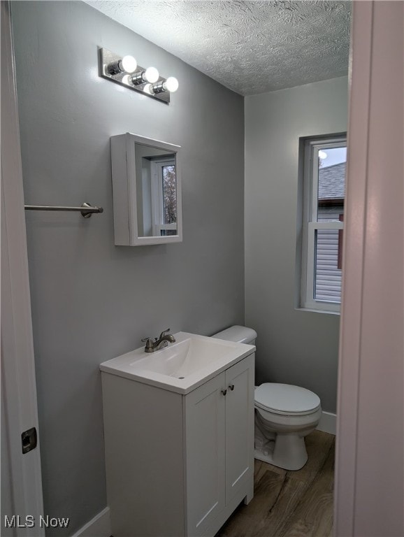 bathroom featuring vanity, hardwood / wood-style floors, a textured ceiling, and toilet