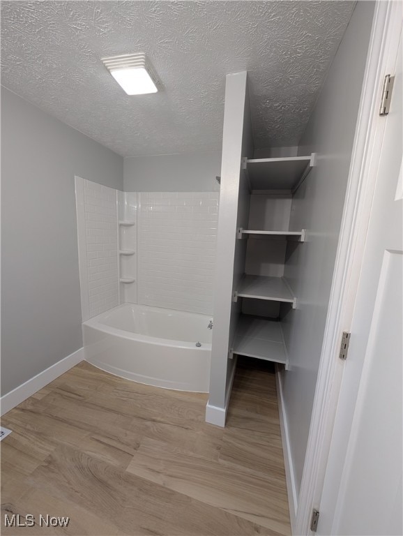 bathroom with shower / bath combination, wood-type flooring, and a textured ceiling