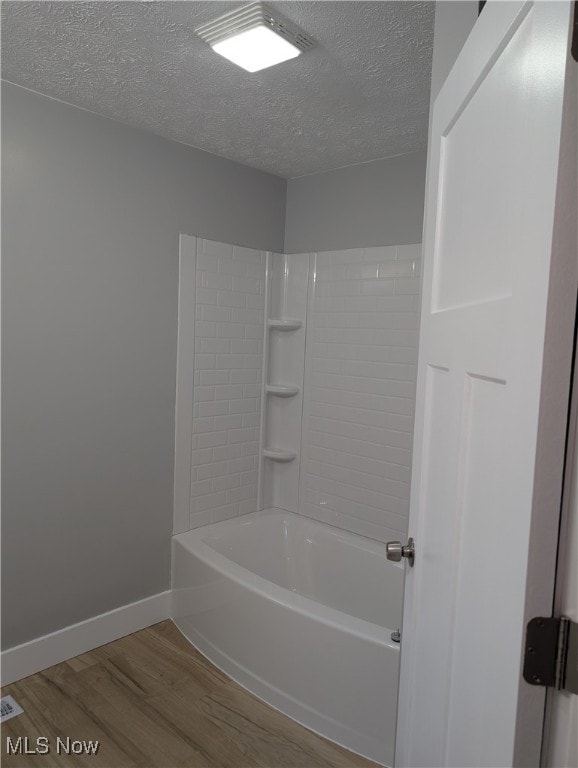 bathroom featuring shower / bathtub combination, a textured ceiling, and hardwood / wood-style flooring