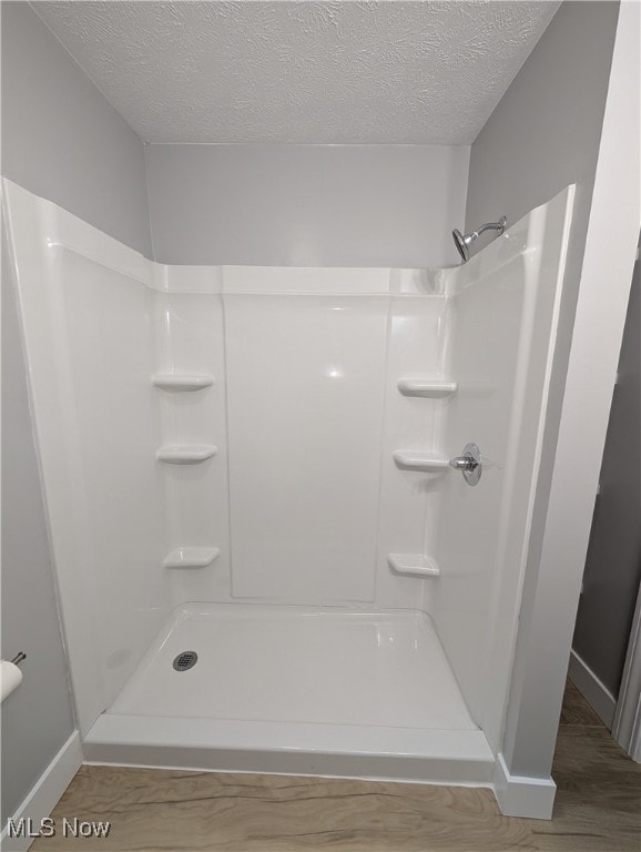 bathroom with wood-type flooring, a textured ceiling, and walk in shower