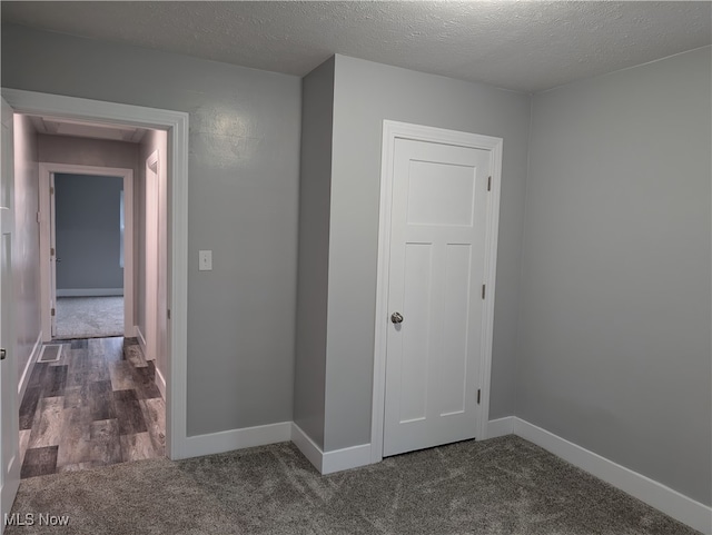 unfurnished room featuring a textured ceiling and dark wood-type flooring