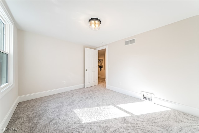 carpeted empty room featuring visible vents and baseboards