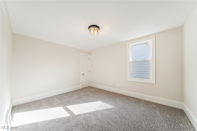 spare room featuring baseboards and light carpet