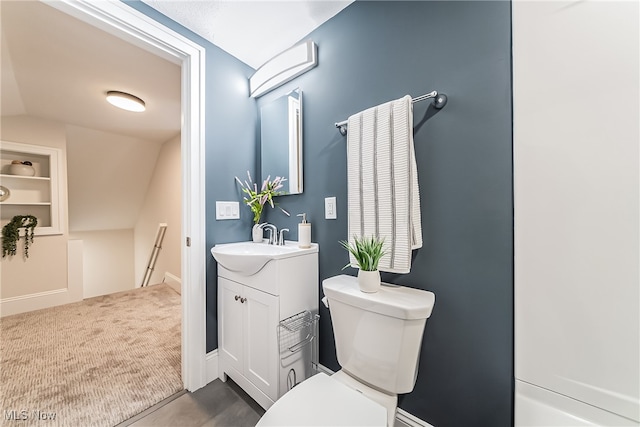 bathroom with vanity, toilet, and lofted ceiling