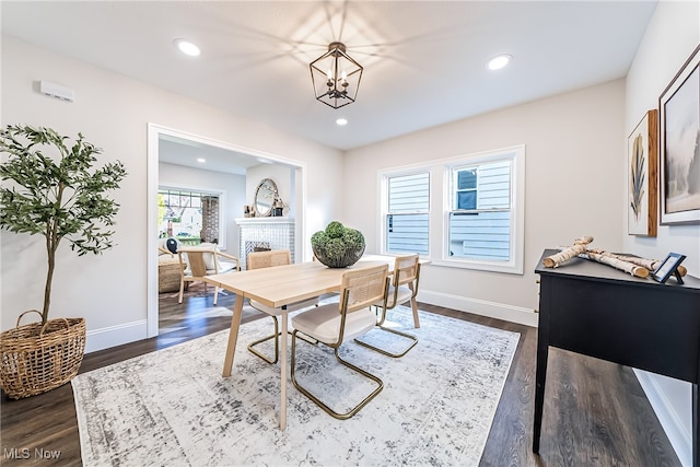 dining room with dark hardwood / wood-style flooring, an inviting chandelier, and a fireplace